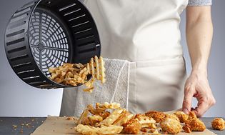 Kvinna häller Airfry poatis på ett bakplåtspapper.