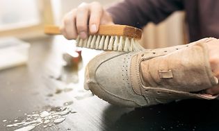 Person brushing a pair of white sneakers