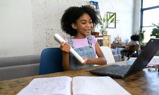 Ung flicka som gör sitt skolarbete med en bärbar dator