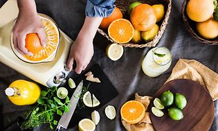 Apelsiner och en hand som använder en ett juicepress-tillbehör