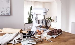 Köksmaskin på ett bord med bakredskap, muffins och ägg