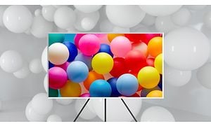Samsung TV:n The Frame på stativ med färgglada ballonger på skärmen.