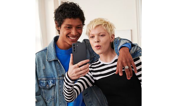Samsung Galaxy S21 FE in the hands of a woman taking a selfie with a man