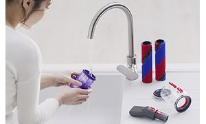 Kvinna tvättar Dyson Omni-Glides tvättbara delar, som gör dammsugaren lätt att underhålla.