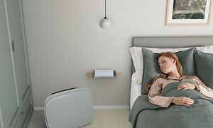 Kvinna sover i sin säng med en grå Well 5 på golvet bredvid sig
