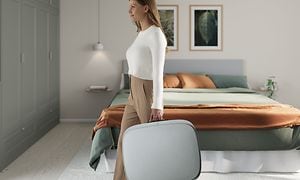 Kvinna i sovrum bär en stor grå Well 5 som en resväska 