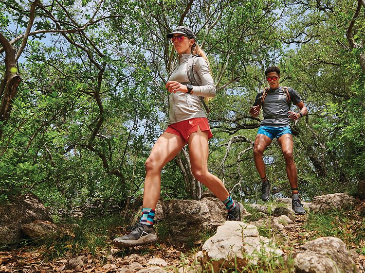 Garmin Fenix 7 på en kvinna och en man som springer i vildmarken