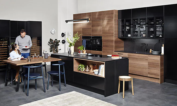 En man serverar mat till en kvinna i ett EPOQ-kök  i serien Epoq Edge och färgerna Blach Ash och Walnut från Elgiganten.