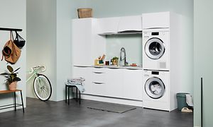 Vit Epoq tvättstuga av serien Gloss White med öppen planlösning i källarlokal med mintgröna väggar.