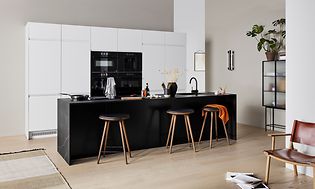 White EPOQ Integra kitchen in an open kitchen solution, with bar chairs and black kitchen island