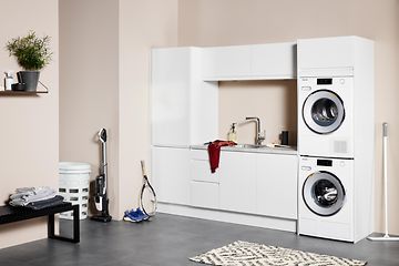 Vit tvättstuga från EPOQ Integra med rosa väggar och tvättmaskin samt torktumlare. 