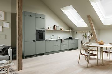 EPOQ Trend kök i färgen sage med öppen planlösning, integrerad ugn och spishäll, runt köksbord med stolar i ljus träfärg.