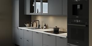 Grått kök från EPOQ Trend i färgen grafit med vit laminat bänkskiva, integrerade svarta vitvaror och vitrinskåp.