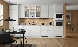 Klassiskt vitt EPOQ Trend kök med öppen planlösning med integrerad ugn i vit färg och svart köksbord med matchande stolar. 