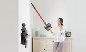 En kvinna som använder Roborocks skaftdammsugare till att rengöra väggen