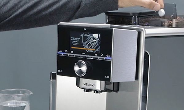 Person som lägger rengöringstablett i en Siemens espressomaskin