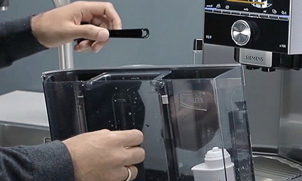 Händer som rengör en Siemens espressomaskin