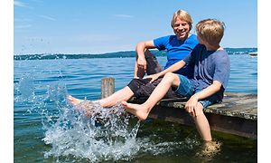 Två unga killar som plaskar fötterna i vatten