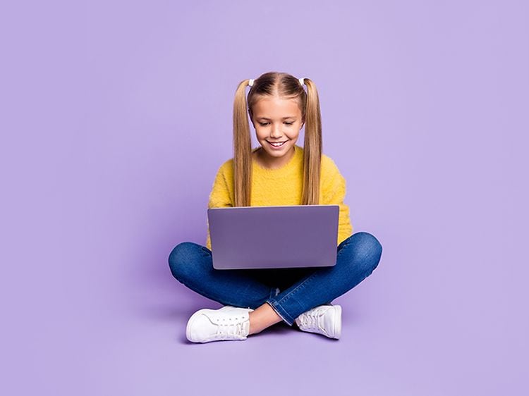 Flicka sitter med en bärbar dator i knäet