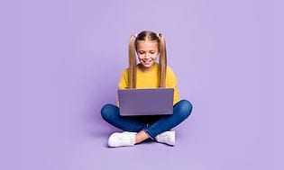 Flicka sitter med en bärbar dator i knäet