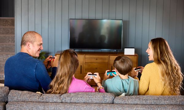 Familj sitter i soffa och spelar på Switch