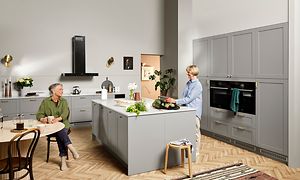 Ljusgrått EPOQ kök i serien Epoq Shaker Steel Grey med köksö, marmorbänkskiva, och integrerade vitvaror.