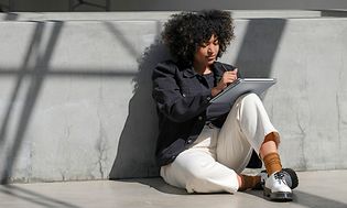 Woman sitting against concrete wall using the laptop