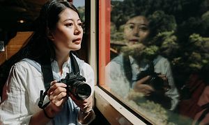 Asiatisk kvinna med en DSLR på ett tåg