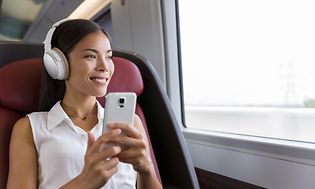 Kvinna på tåg med brusreducerande hörlurar