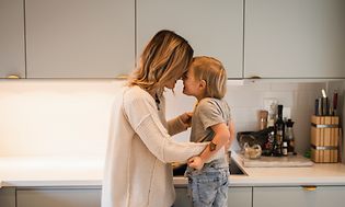 Mamma och son kramas och skrattar i ett ljust kök