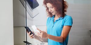 Ung kvinna håller i en smartphone i en butik
