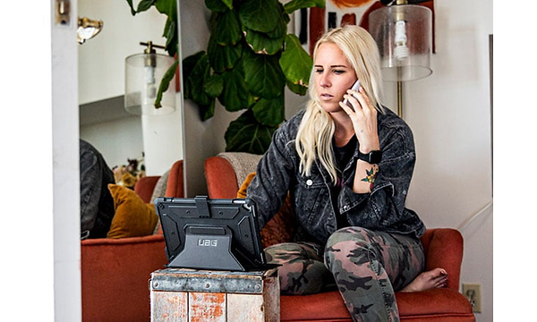 UAG skal och fodral till iPad- och surfplatta: En kvinna sitter i telefon och ser på sin padda med UAG fodral.