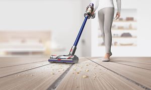 Kvinna som dammsuger golver med Dysons sladdlösa dammsugare