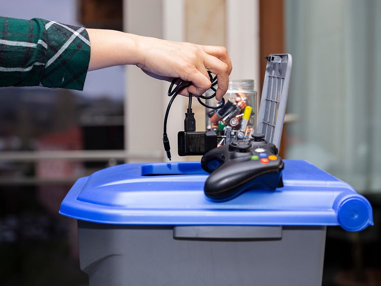 En hand som kastar ut lite gammal elektronik
