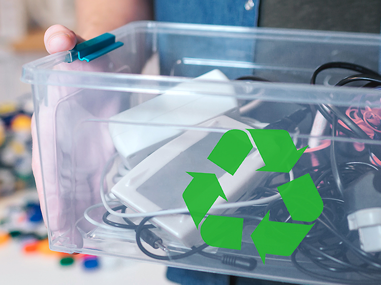 Sustainability - Recycling - A man holding a box with old electronics and a recycle logo