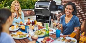 Personer som äter middag och en Weber pelletsgrill i bakgrunden
