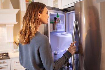 Kvinna tittar in i kylskåp med belysning