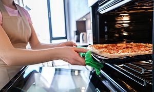 En kvinna tar ut en pizza ur en ugn