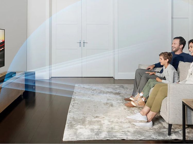 Familj som sitter i vardagsrummet och tittar på TV med ljud från Sony Soundbar.