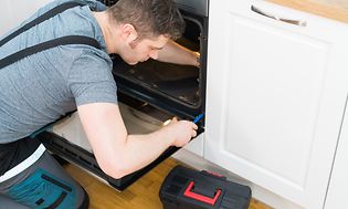 MDA-Ovens-Man installerar en ugn i ett vitt kök