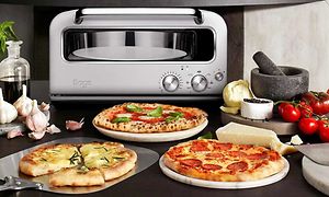 Olika typer av pizza på ett bord och en Sage pizzaugn i bakgrunden