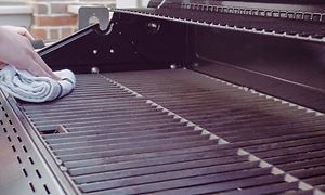 En hand som rengör en grill med en trasa