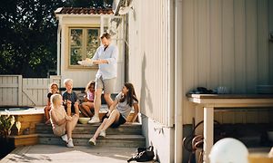 Man som bär ut mat och barn som sitter utomhus på trappan