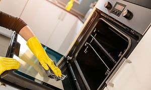 Person cleaning the front of an oven