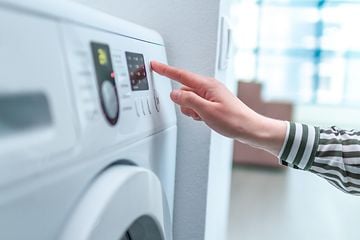 En person använder displayen och knapp för att välja program på tvättmaskin
