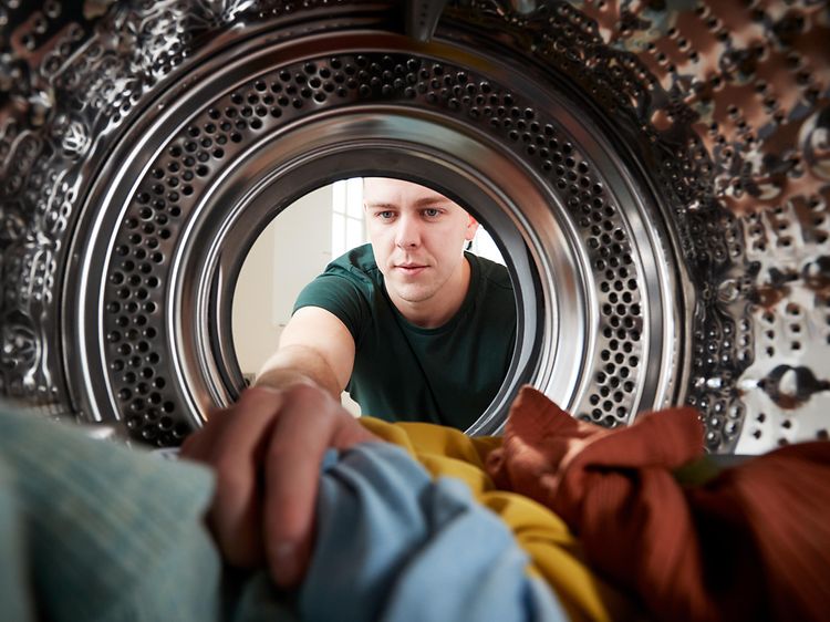 Man lägger in kläder i en tvättmaskin, sett inifrån tvättmaskinen
