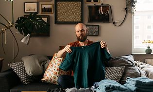 Man som viker rena kläder i ett vardagsrum