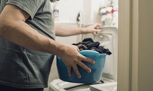 Man håller i en balja full av kläder