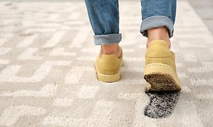 Gula skor lämnar ett smutsigt fotavtryck på en beige matta