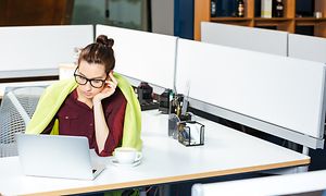 Kvinna på kontor med filt runt sig